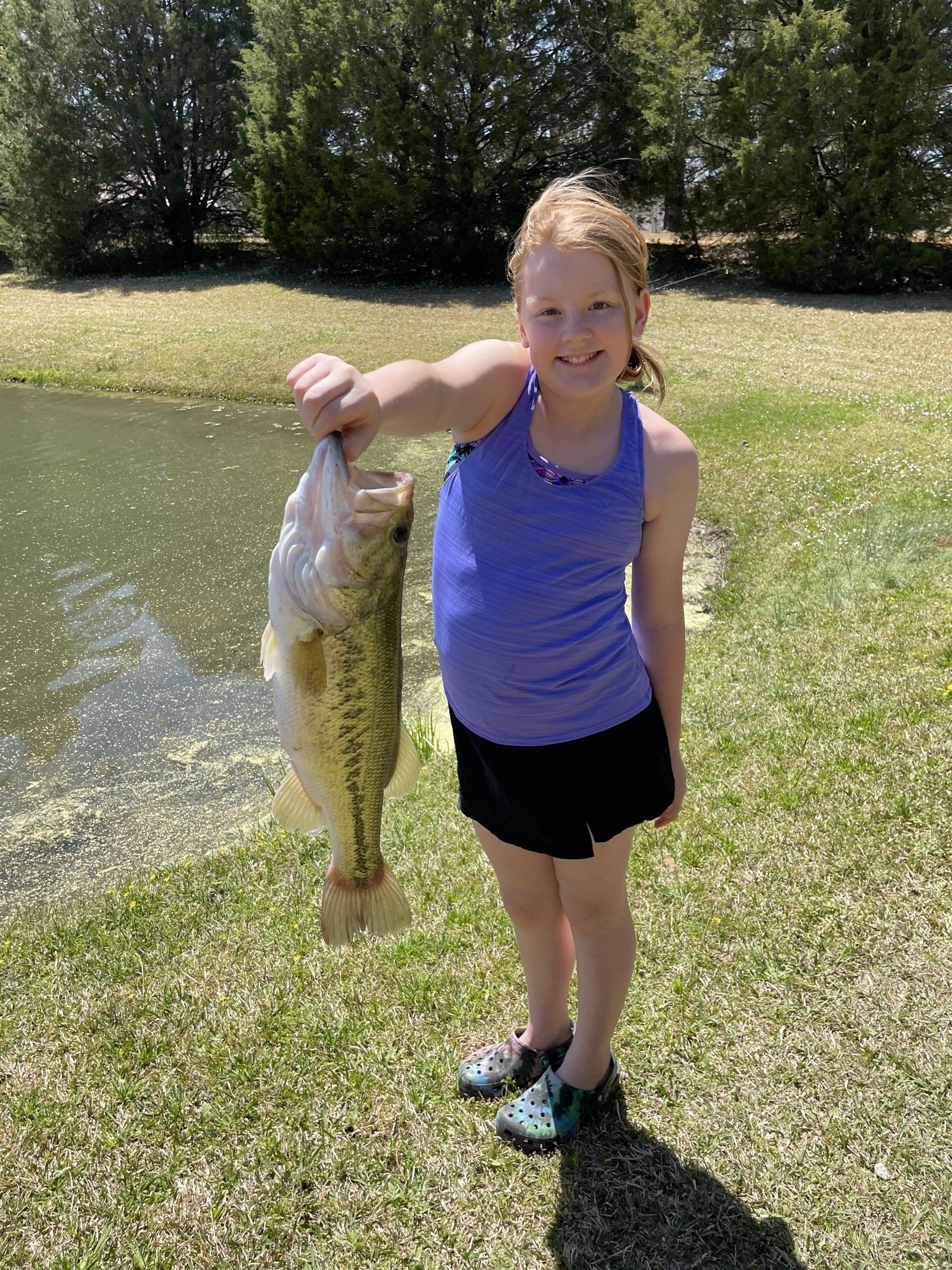 A young girl is holding a large fish in her hands.
