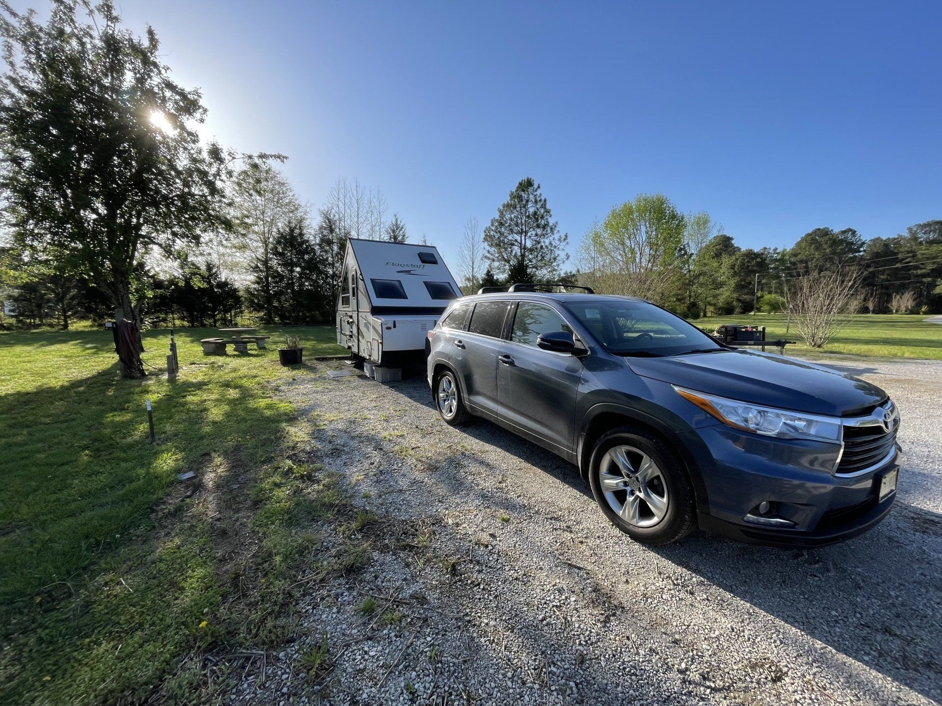 A car is towing a trailer down a gravel road.