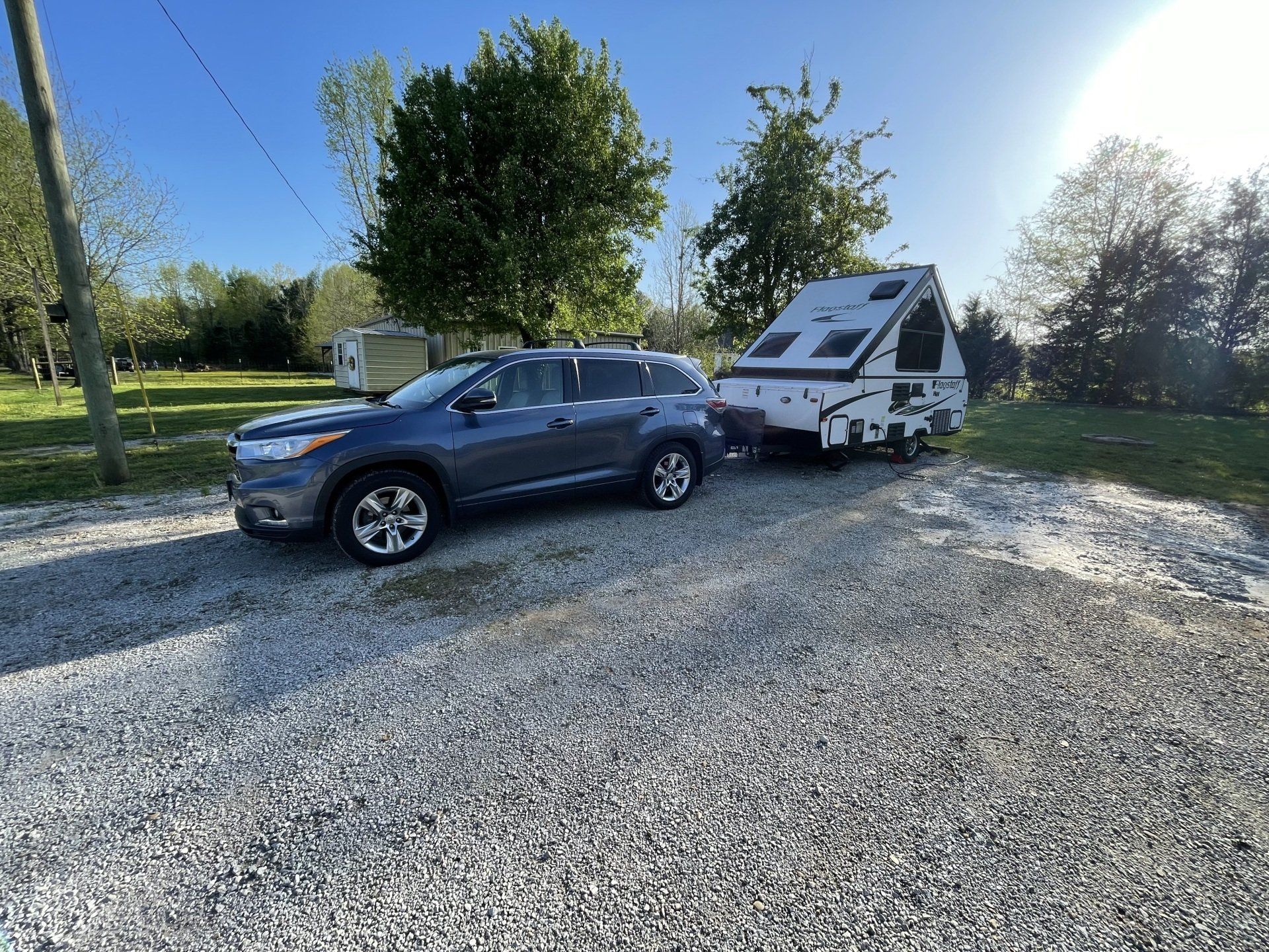 A car is towing a trailer down a gravel road.