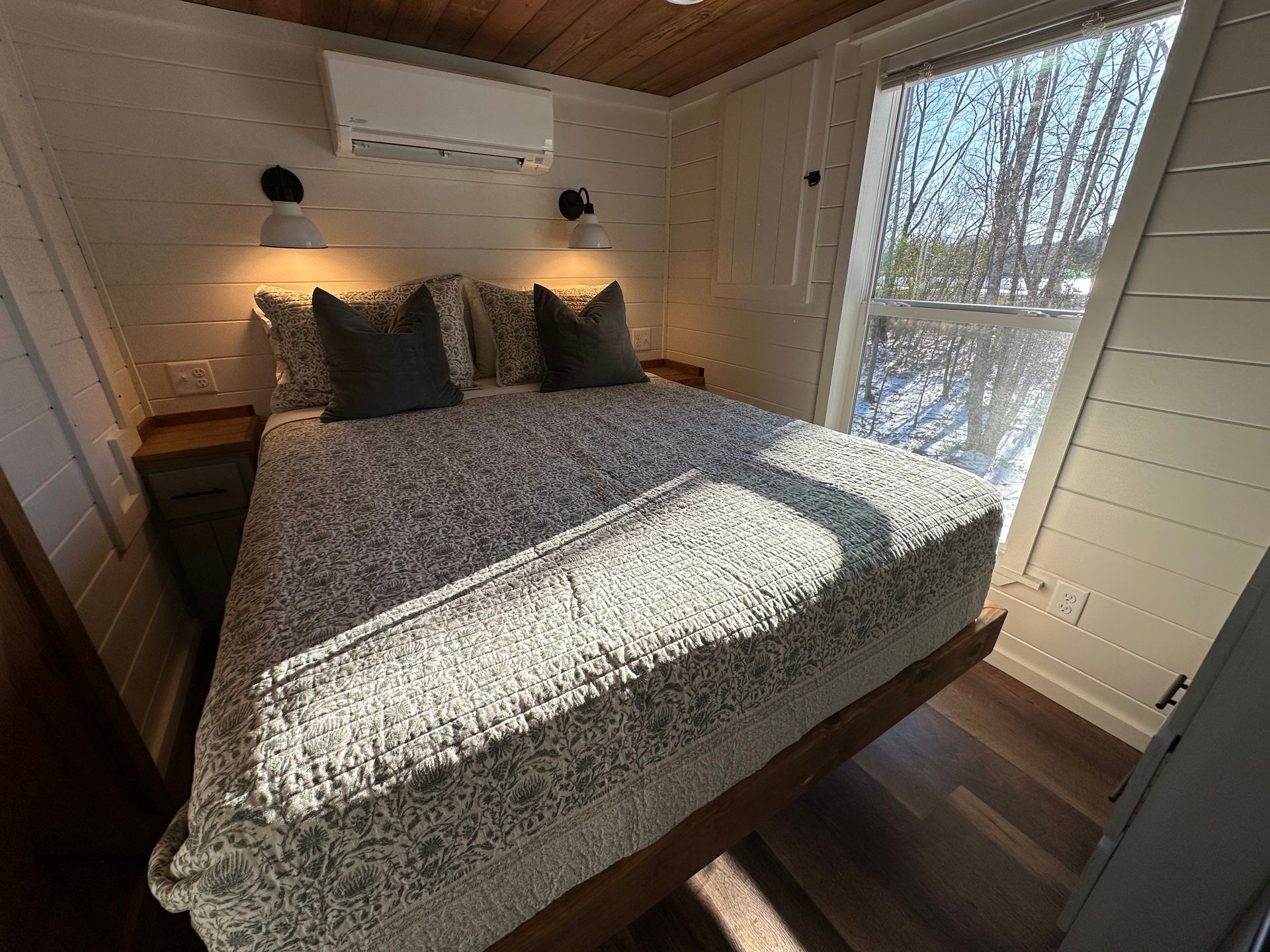 A bedroom with a bed and a window with trees in the background.