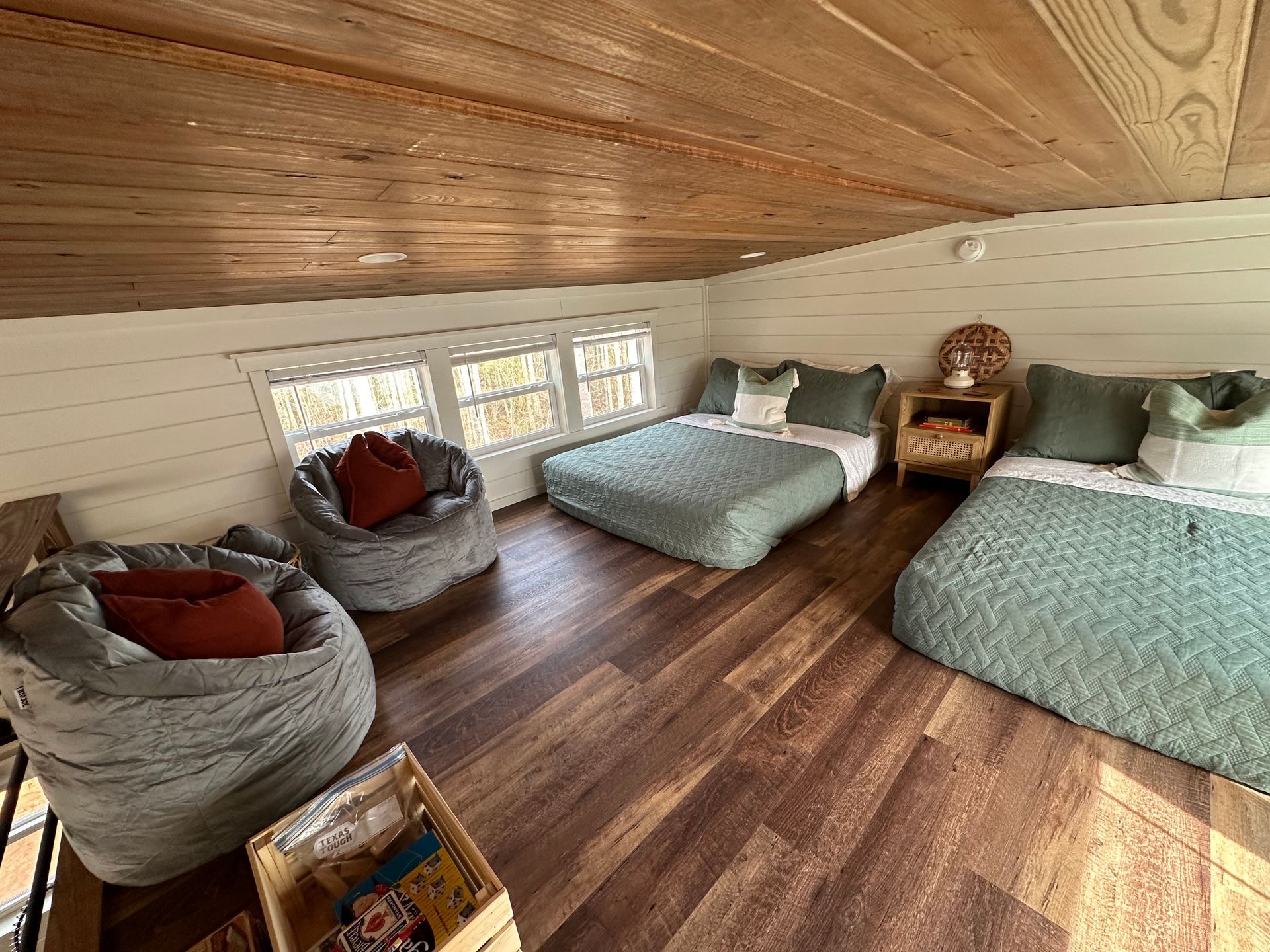 A bedroom with three beds , bean bag chairs , and a window.