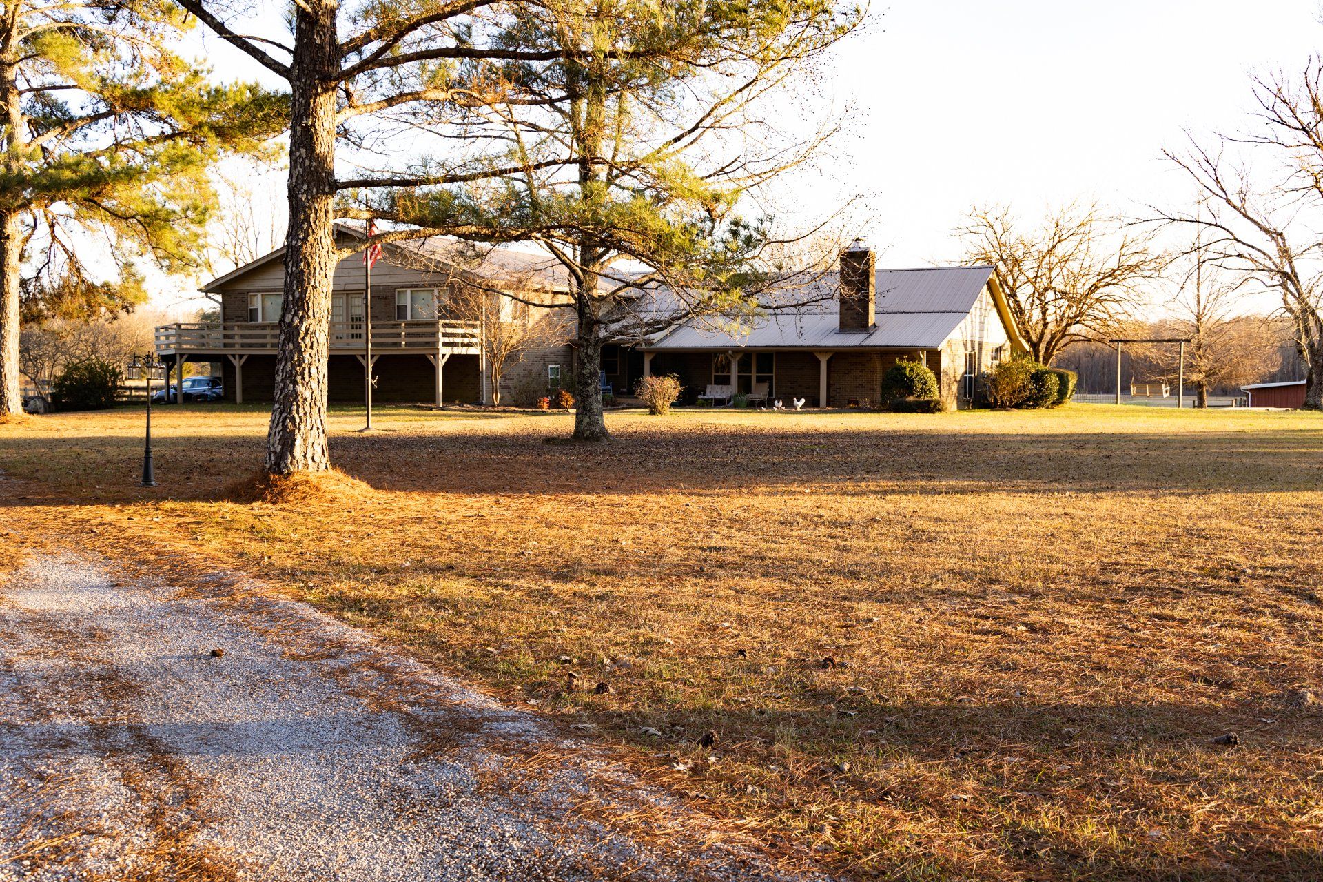 A large house sits in the middle of a lush green field surrounded by trees.