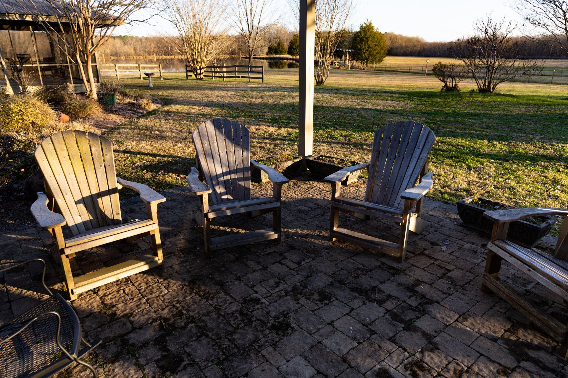 A group of wooden chairs are sitting on a brick patio.