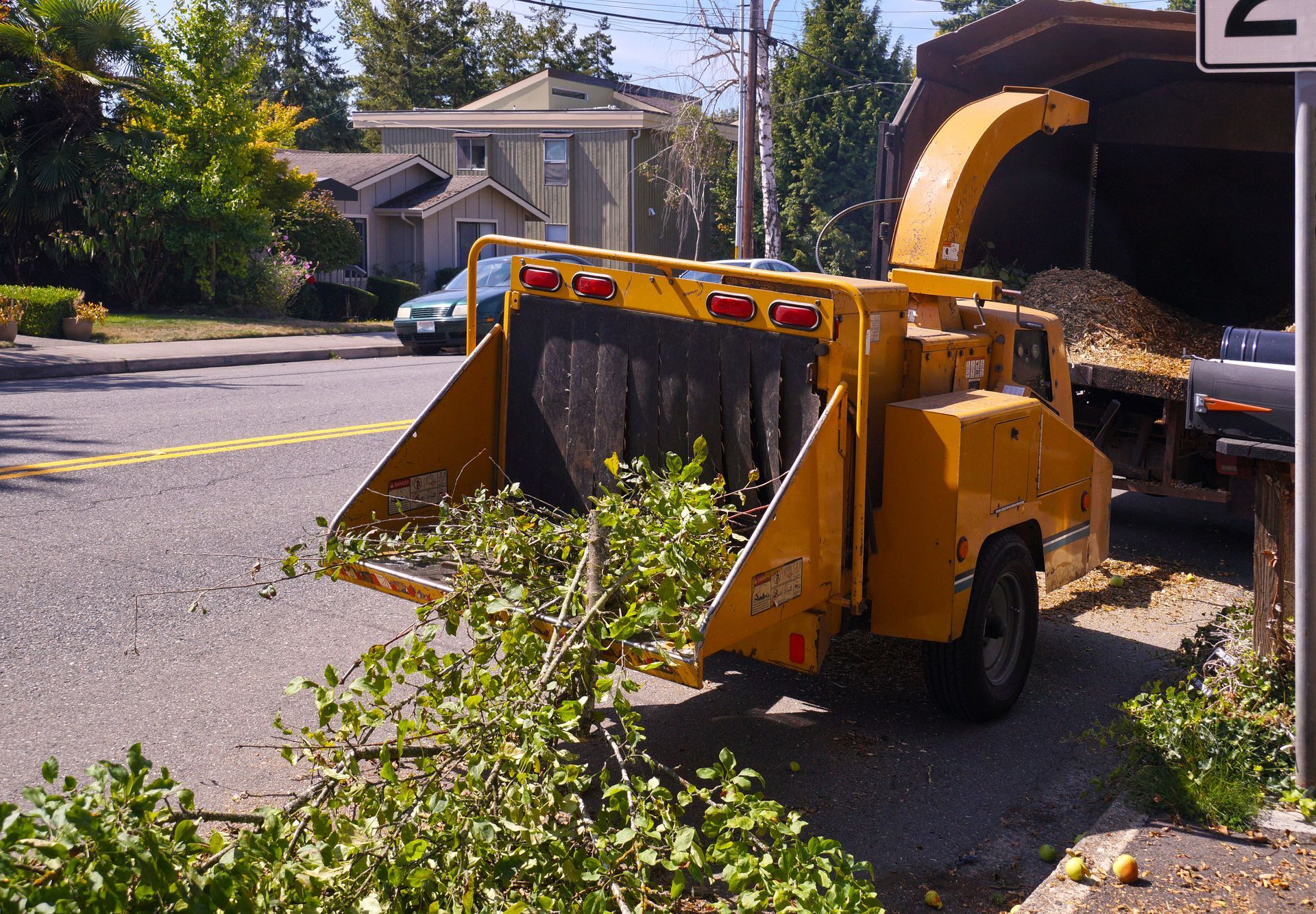 Wood chipper in action, chopping branches during suburban cleanup.