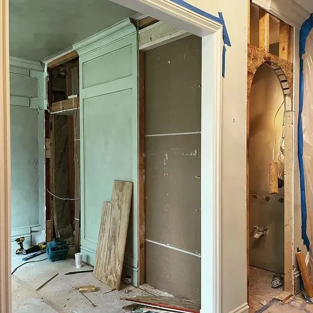 Interior under renovation with green built-in cabinetry, exposed walls, and construction debris.
