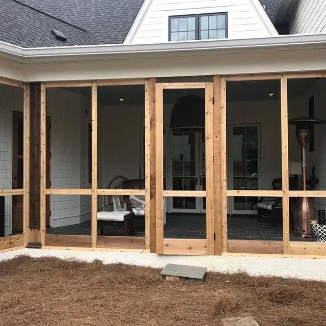 Unfinished screened porch with wooden framing and open doorways on a house exterior