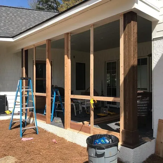 Partially framed sunroom addition with blue ladder and exposed wooden posts under a roof overhang