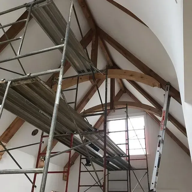Scaffold inside a church with exposed wooden beams and a tall arched ceiling