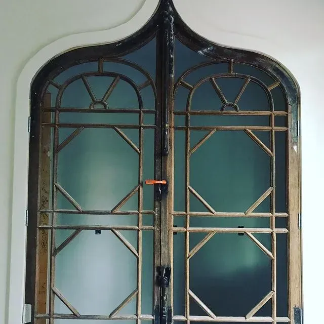 Decorative arched metal-and-glass window with blue panels and gold trim