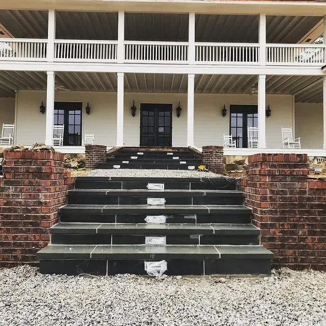 Front view of a house with wide brick steps, white porch columns, and dark shutters