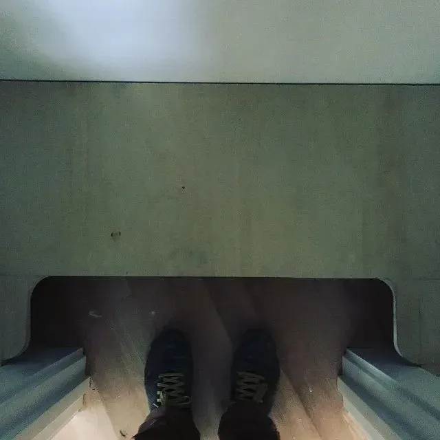 Feet in sneakers resting inside a small wooden alcove with blue side rails.