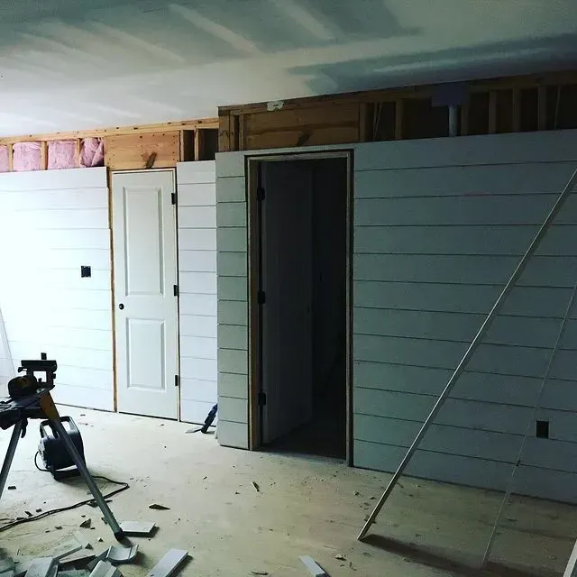 Partially finished room with white paneled walls, open doorways, and construction tools on the floor