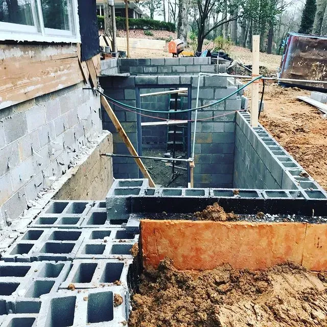 House foundation under construction with cinder block walls, trench, and exposed soil