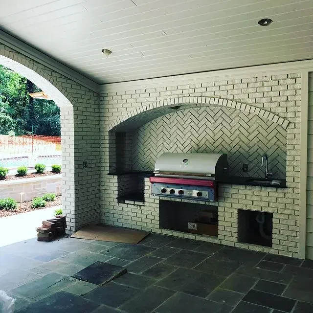 Covered outdoor patio with white brick built-in grill and slate tile floor