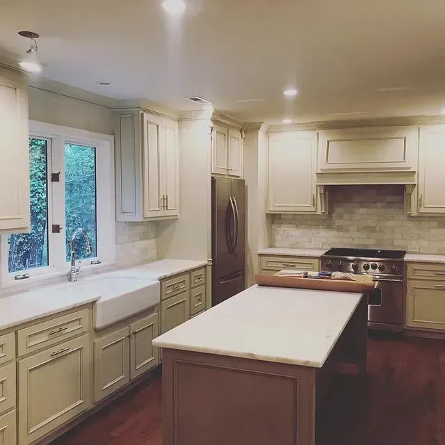 Bright kitchen with cream cabinets, white island, hardwood floors, and a window over the sink.