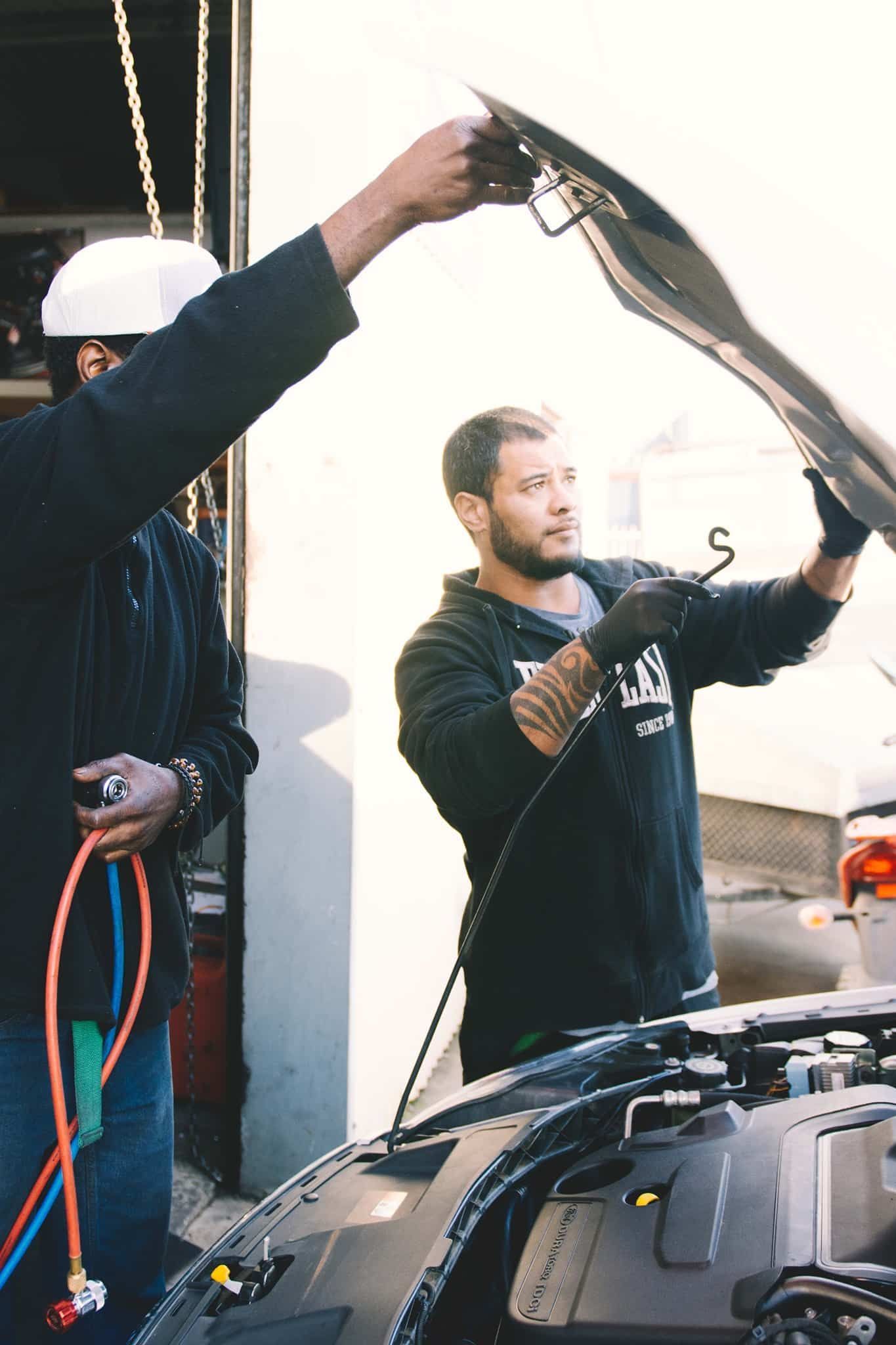 Two mechanics inspecting a car engine under the bonnet at North Geelong Automotive