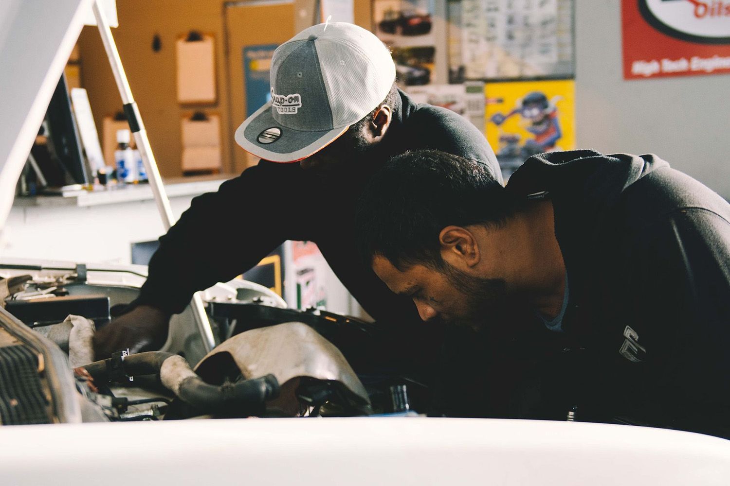 Two mechanics inspecting a car engine under the bonnet at North Geelong Automotive