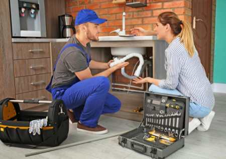 Plumber in kitchen discussing a drain problem