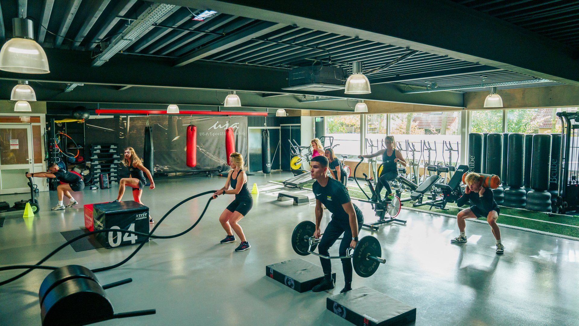 Een personal trainer helpt een vrouw bij een oefeninig op een machine in een sportschool.
