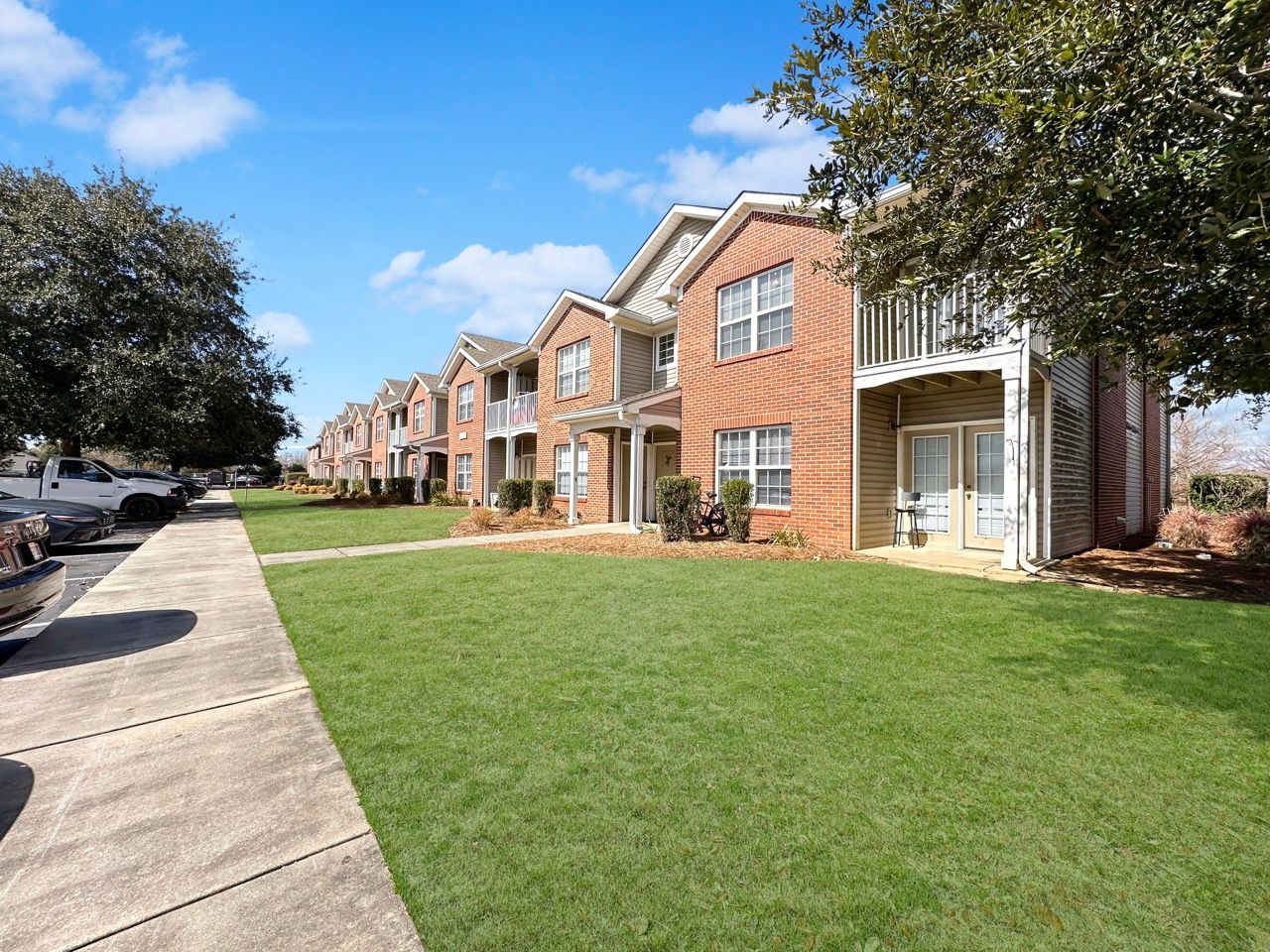 Apartment complex with red brick, green lawn, and blue sky.
