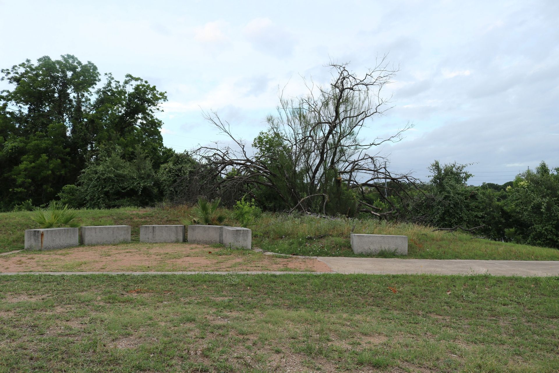 a concrete bench sits in the middle of a grassy field