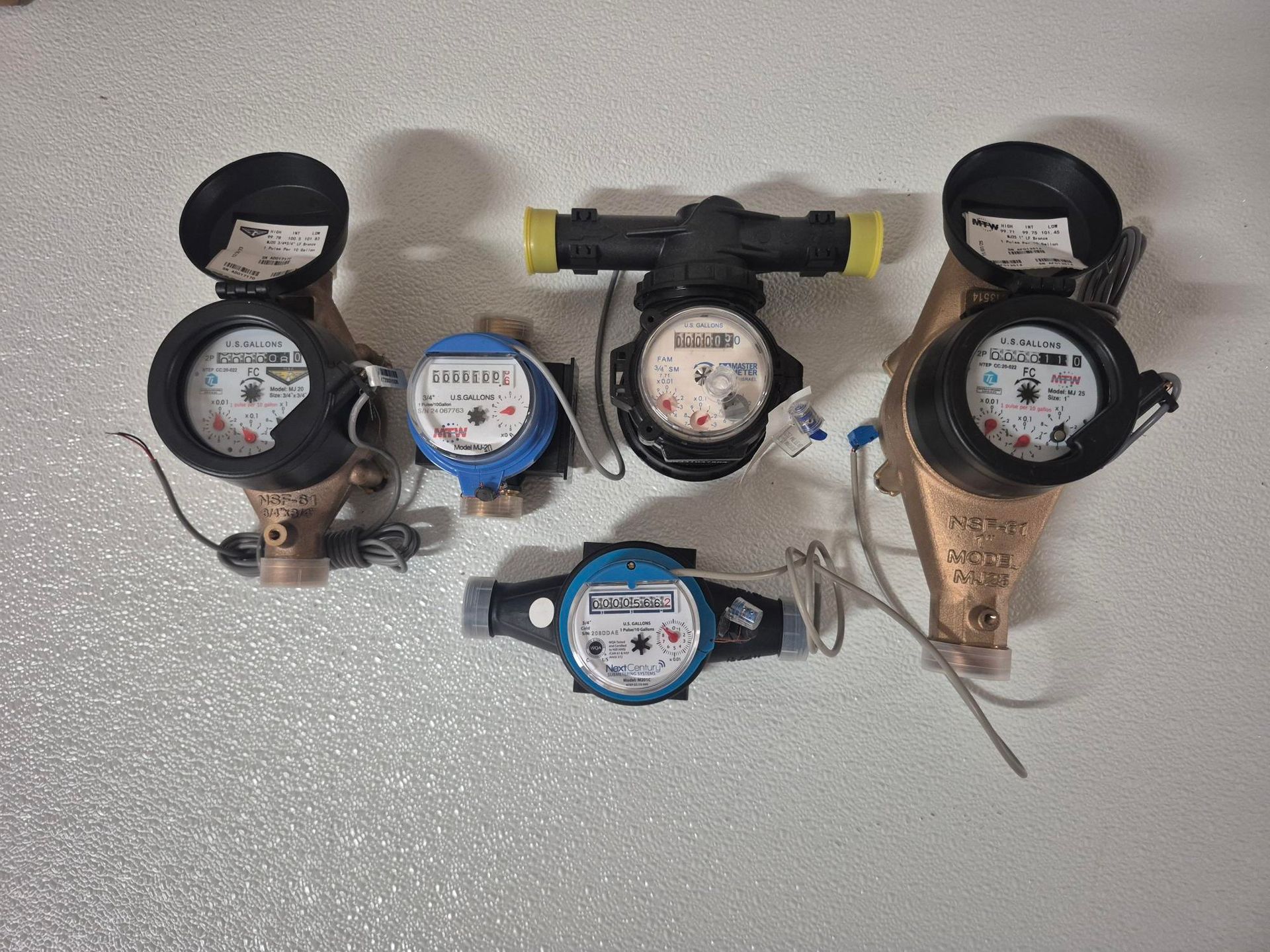 Row of water meters with red and blue rings mounted on a wall