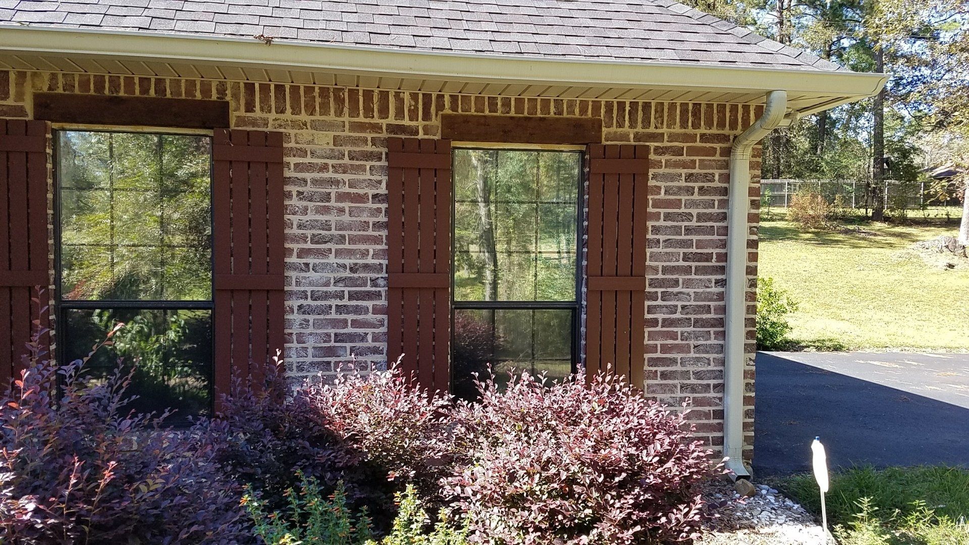 A brick house with brown shutters on the windows