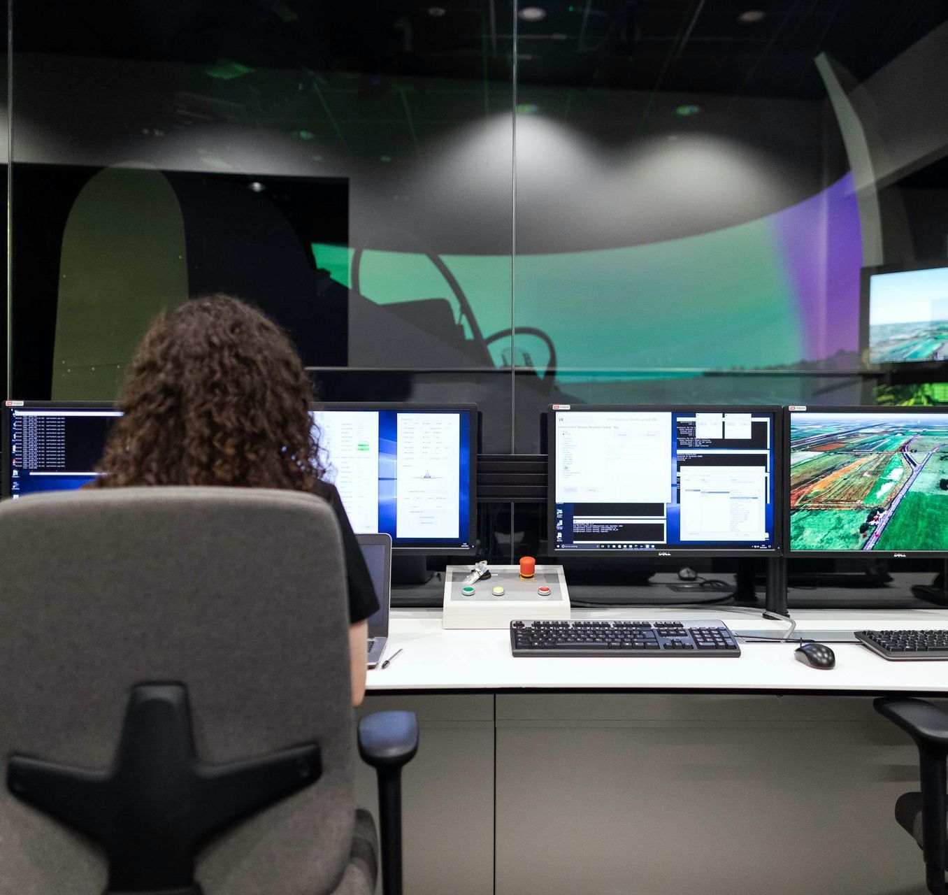 A man is typing on a keyboard in front of two computer monitors