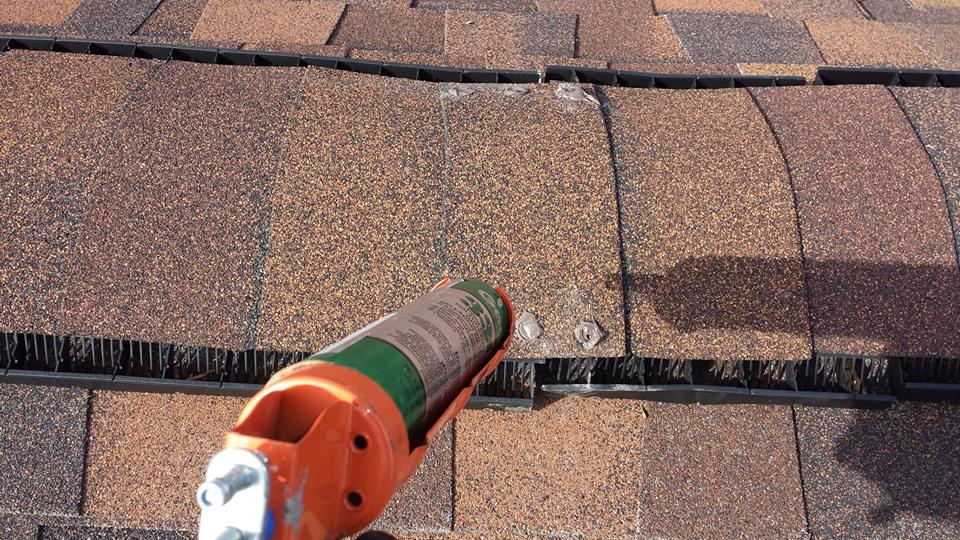 Handheld power tool applying sealant to roof shingles near a seam