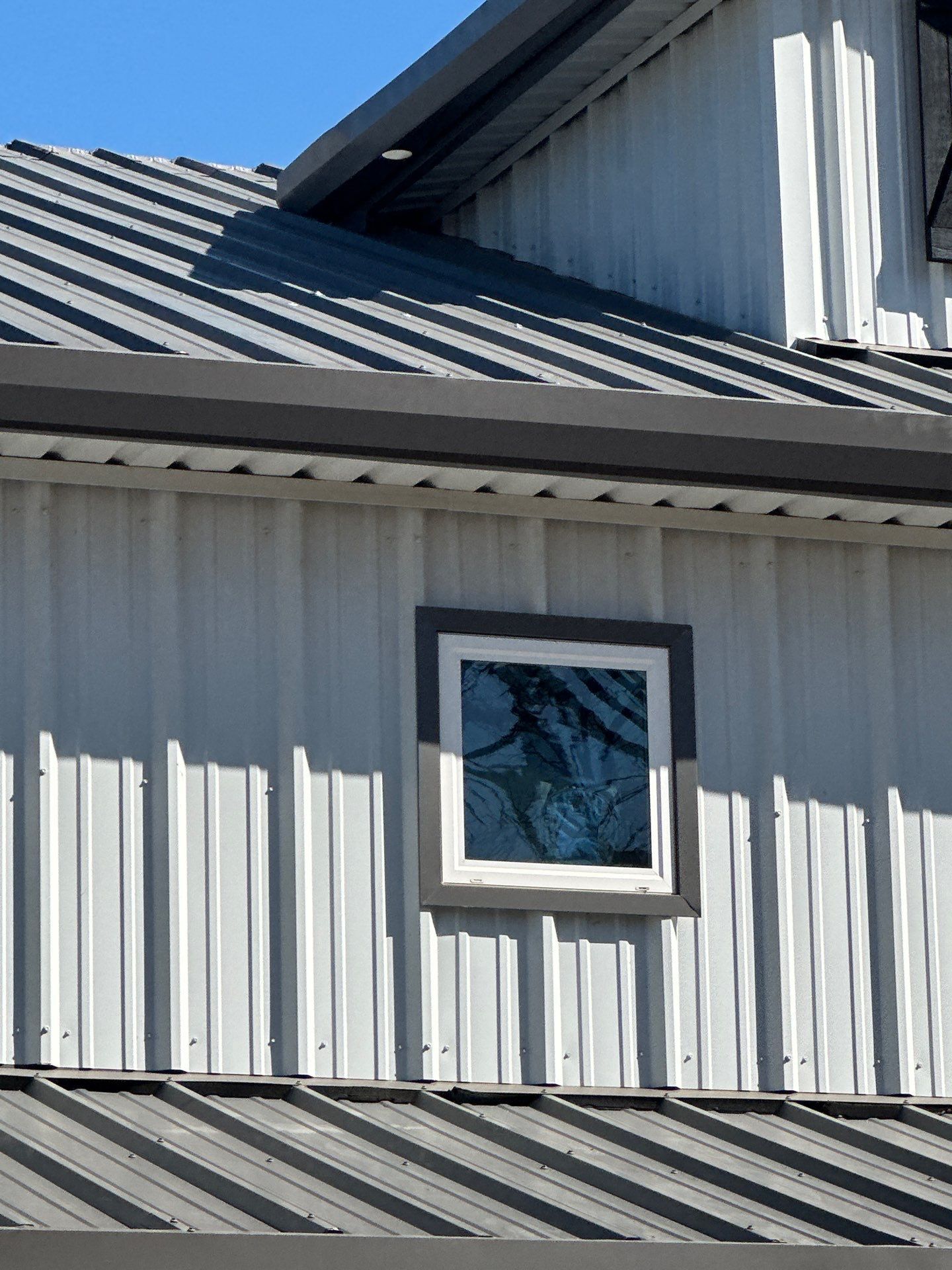 White metal building exterior with a small window and gray sloped roof panels