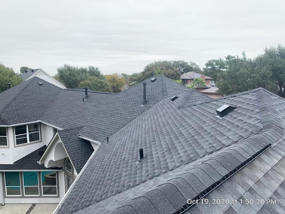 Gray shingle roof with multiple dormers and skylights on a house, seen from above under cloudy sky