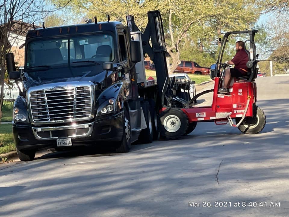 Tow truck operator driving a red tow trike beside a black semi-truck on a road