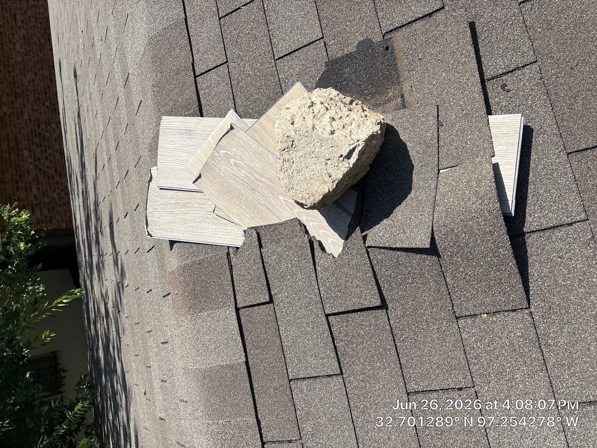 Broken roof shingles with several loose pieces on a weathered rooftop.