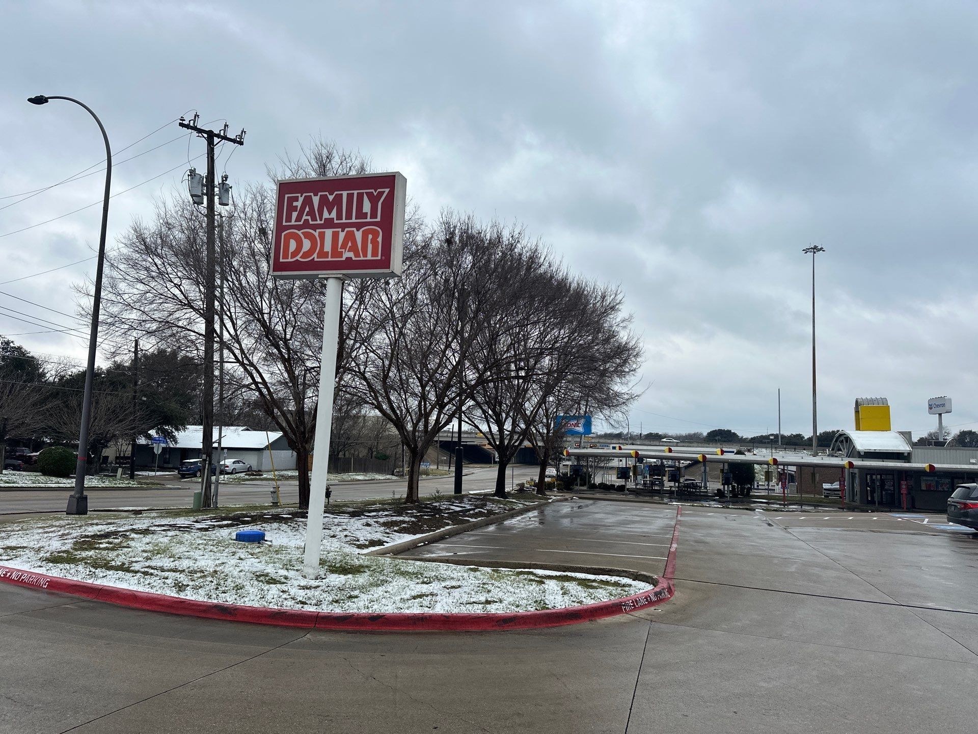 Shopping center parking lot with a red Family Dollar sign on a snowy, overcast day