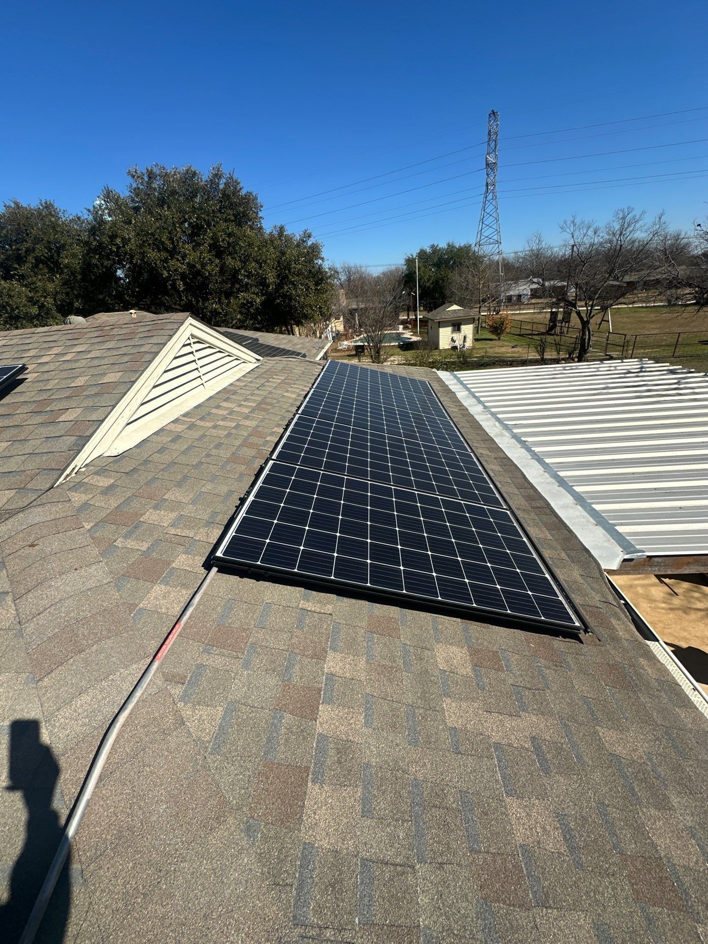 Solar panels installed on a shingled rooftop under a clear sky