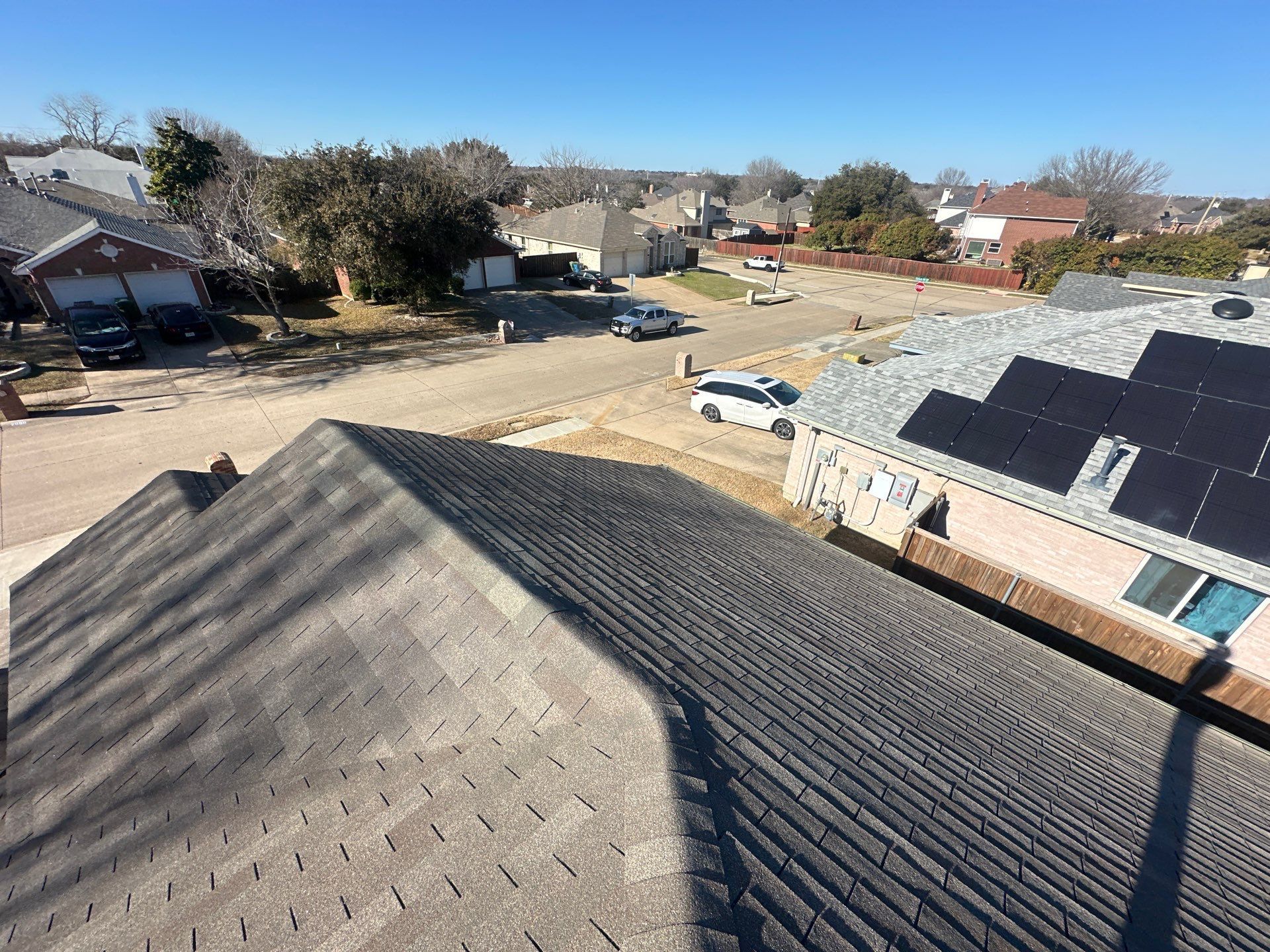 Rooftop view of a suburban neighborhood with solar panels and a clear blue sky.