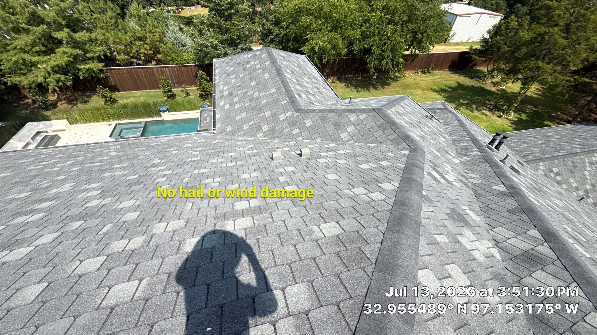 Shingled roof with a chimney, overlooking a backyard pool and trees from above
