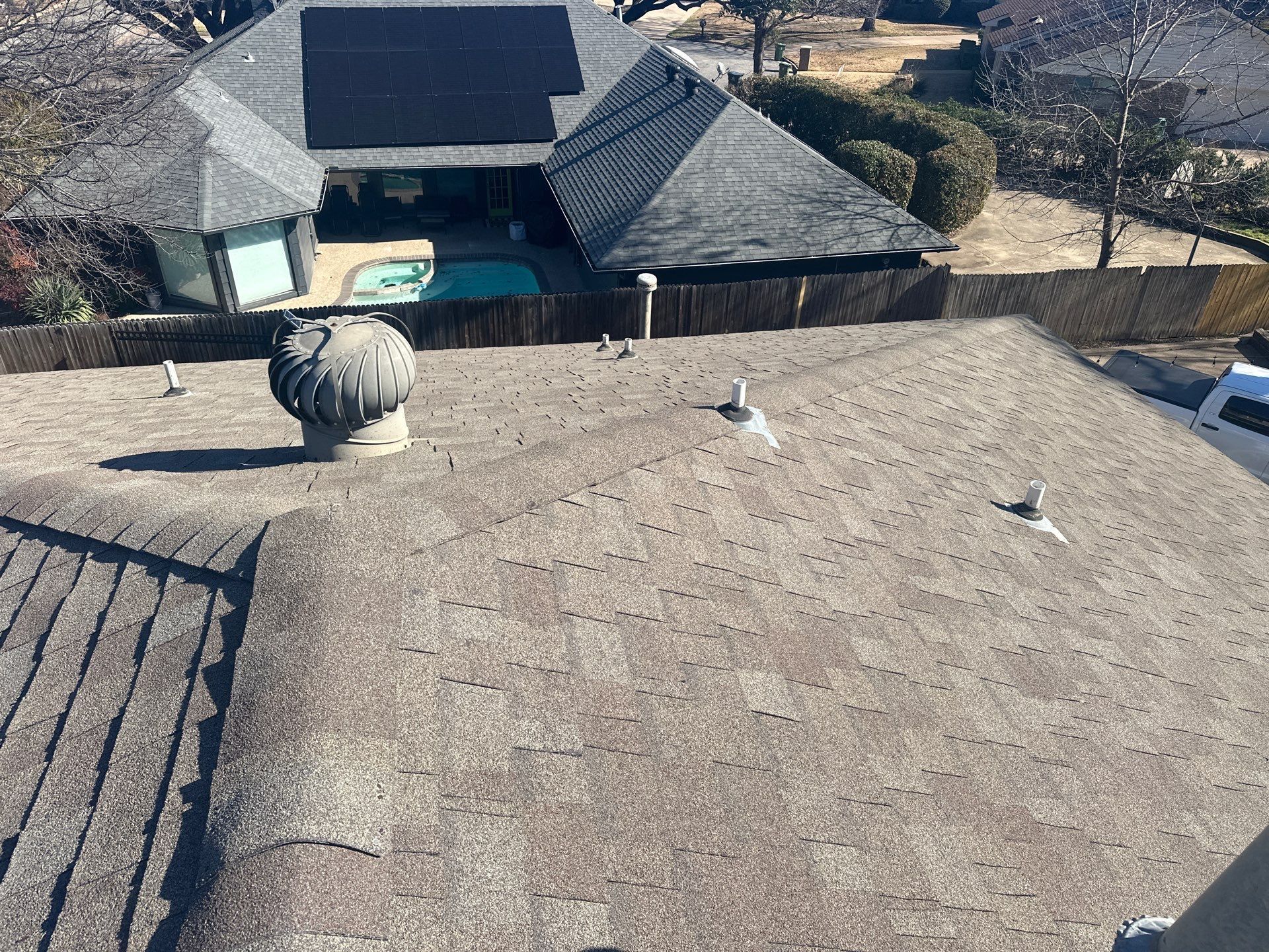 Rooftop with gray shingles, skylights, and a decorative sphere; neighboring houses in the background.
