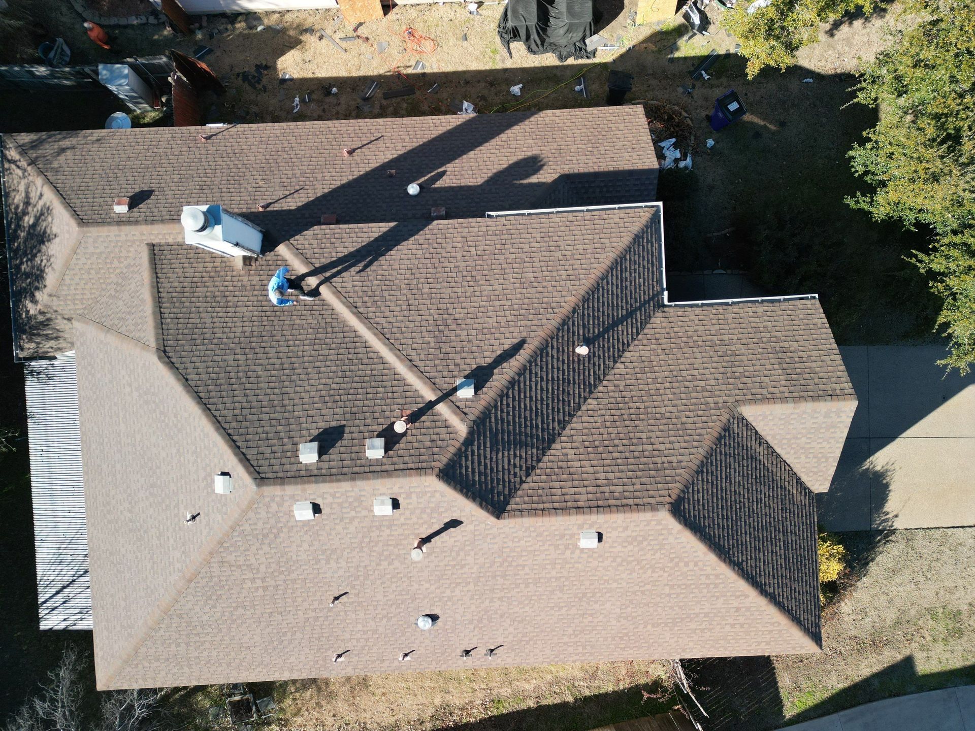 Aerial view of a brown shingled house roof with multiple vents and skylights.