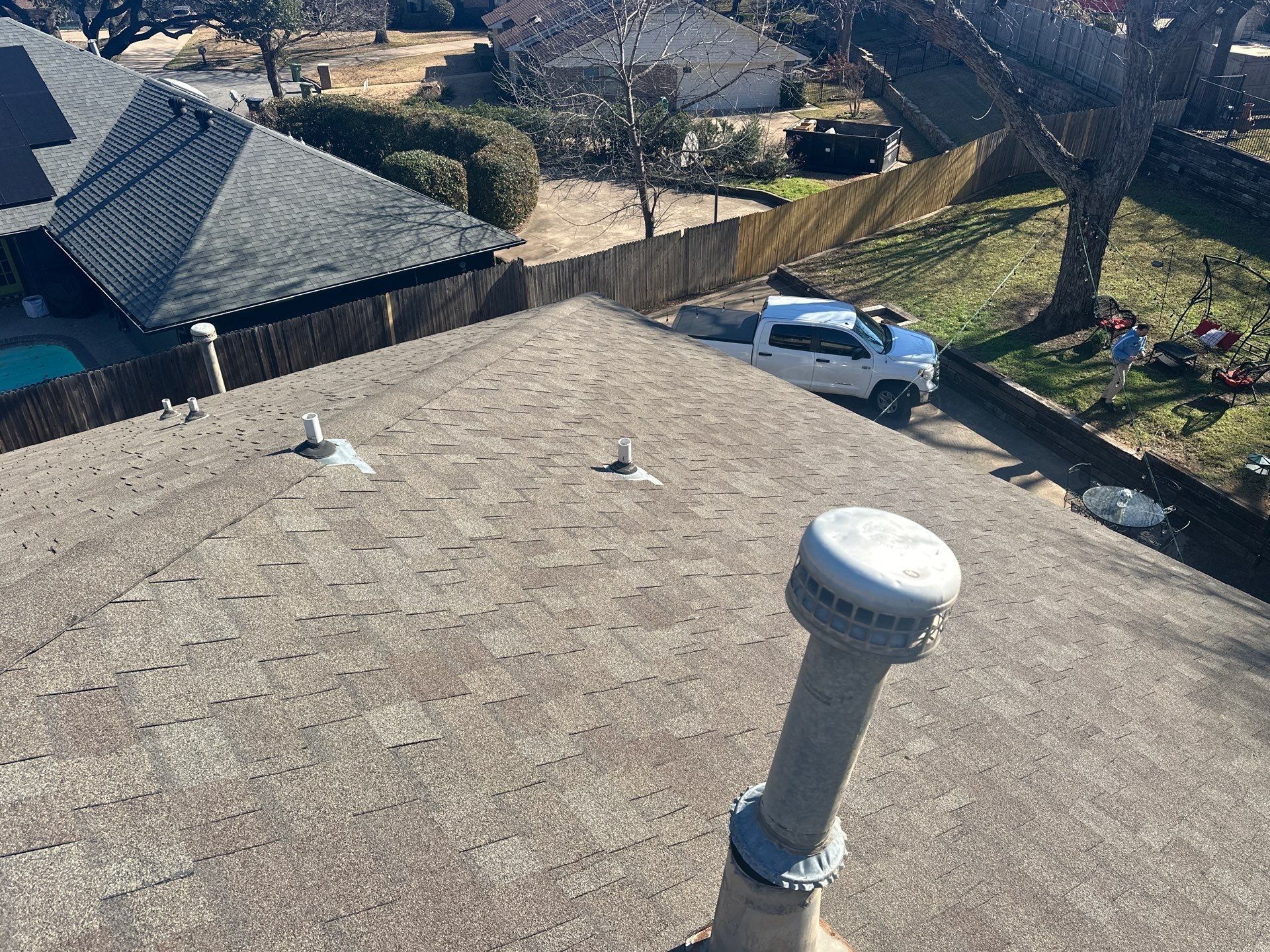 View from a rooftop over a neighborhood, with a white van parked below and a vent pipe in the foreground