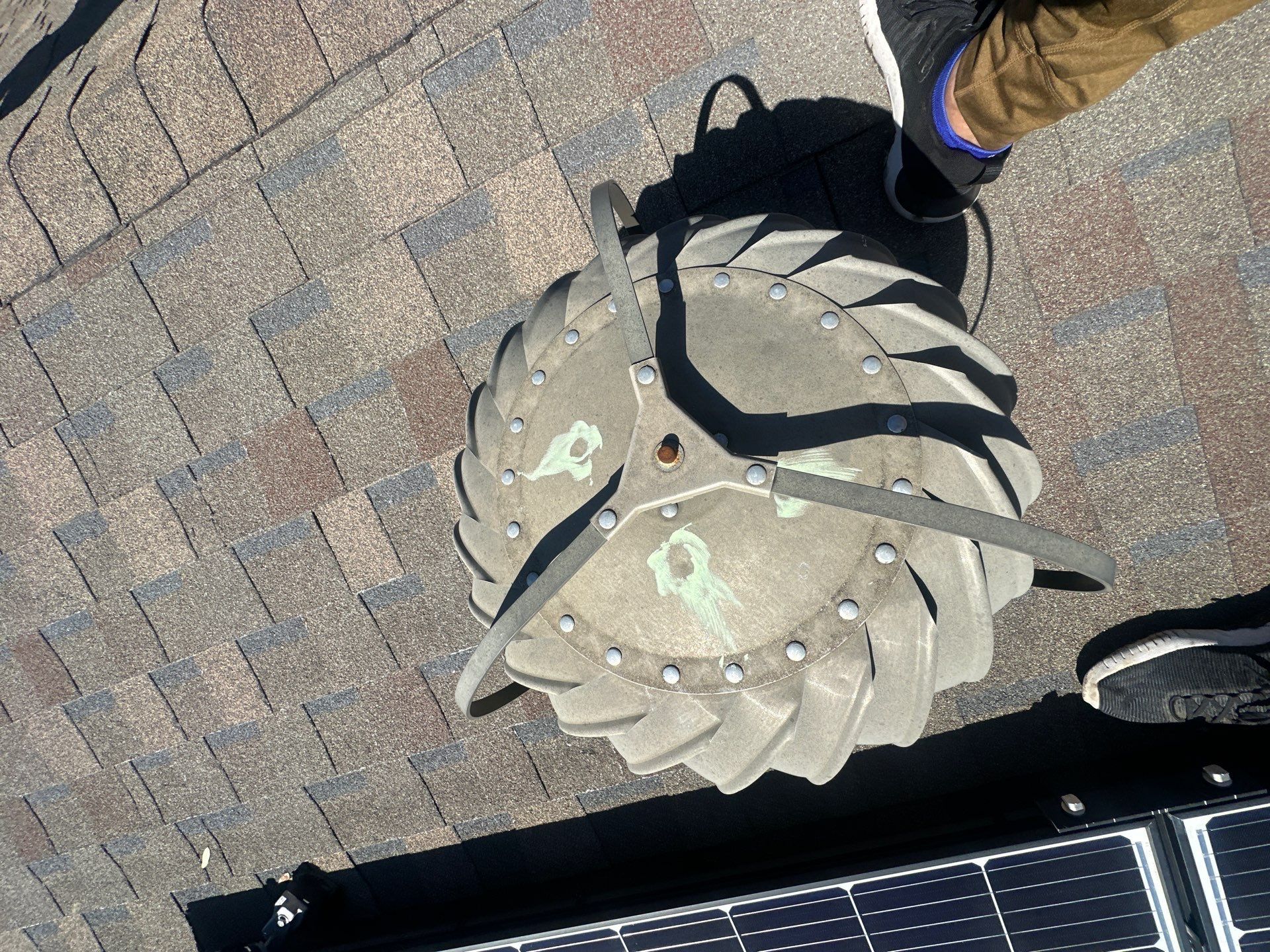 Top-down view of a small gray spiral pumpkin decoration on brick pavement near people’s shoes