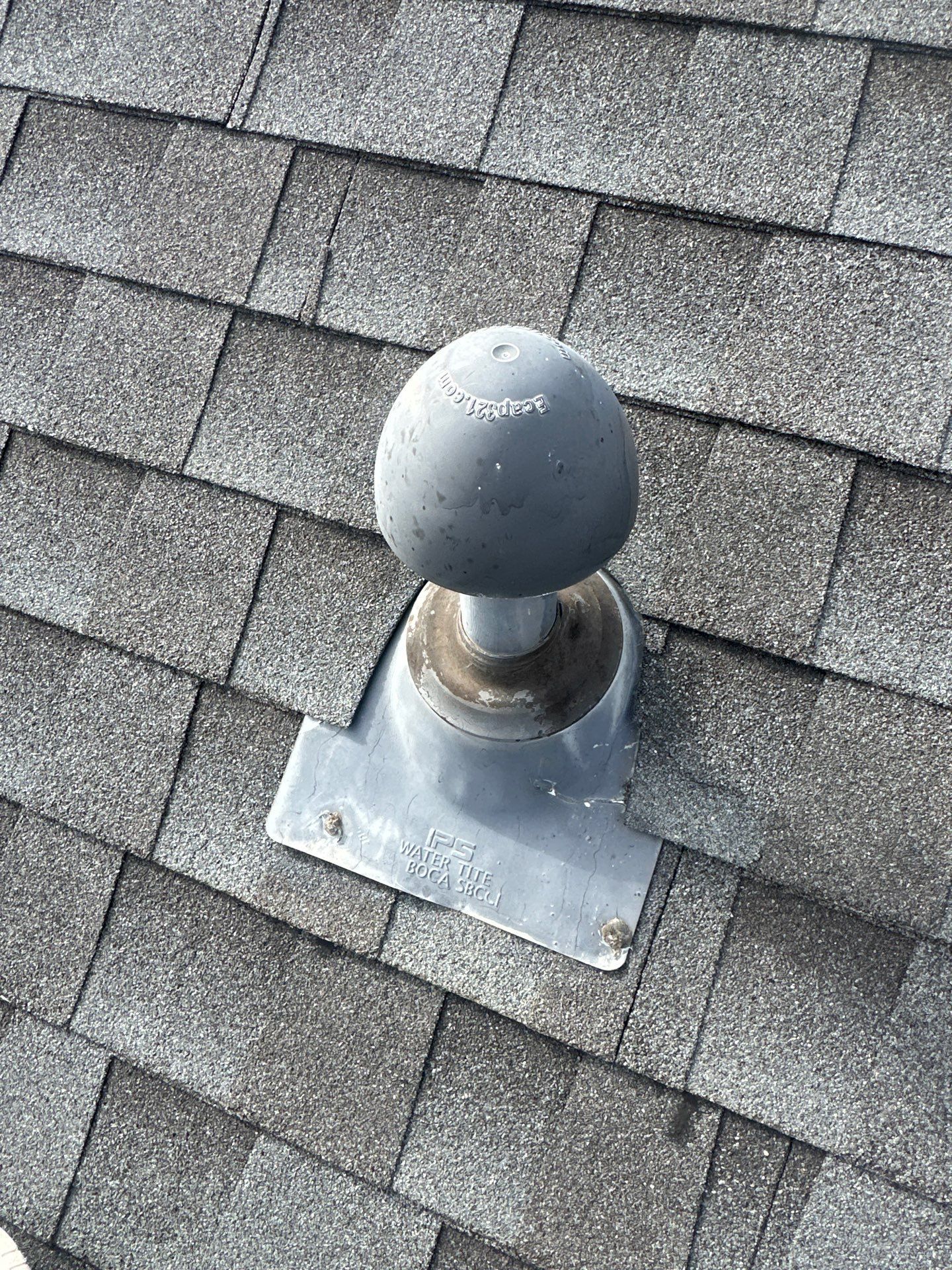 Roof vent with a black spherical cap mounted on gray shingles