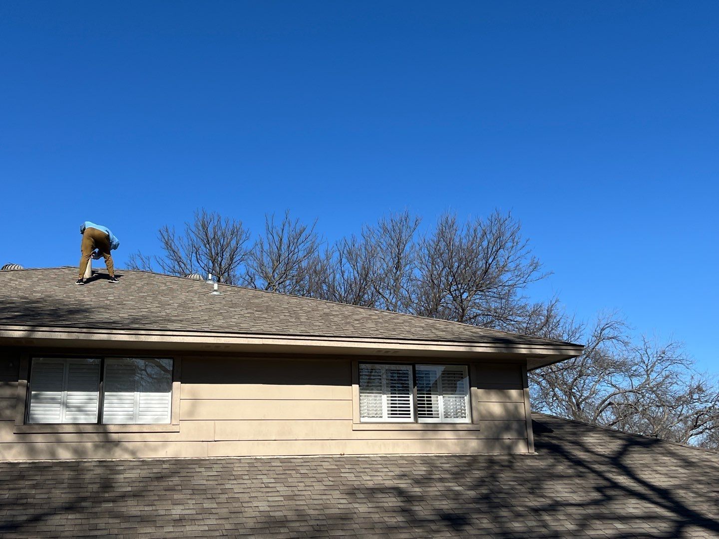 Person working on a roof under a clear blue sky