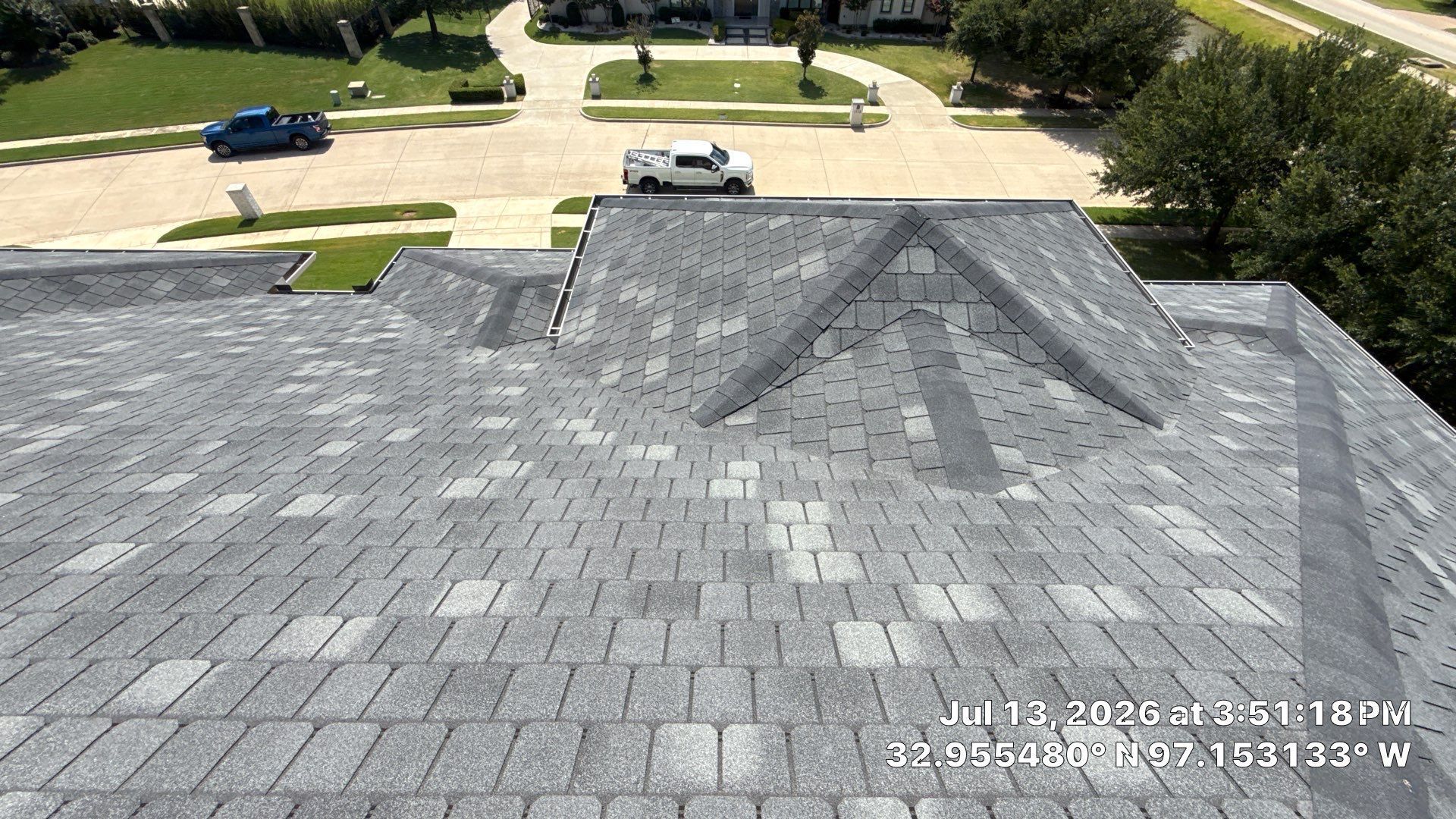 Gray shingle roof with dormer above a suburban street and trees