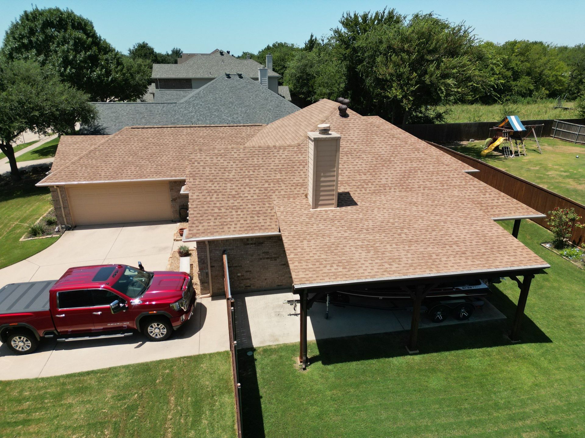 Aerial view of a suburban house with a red pickup truck in the driveway and a covered patio over the backyard.