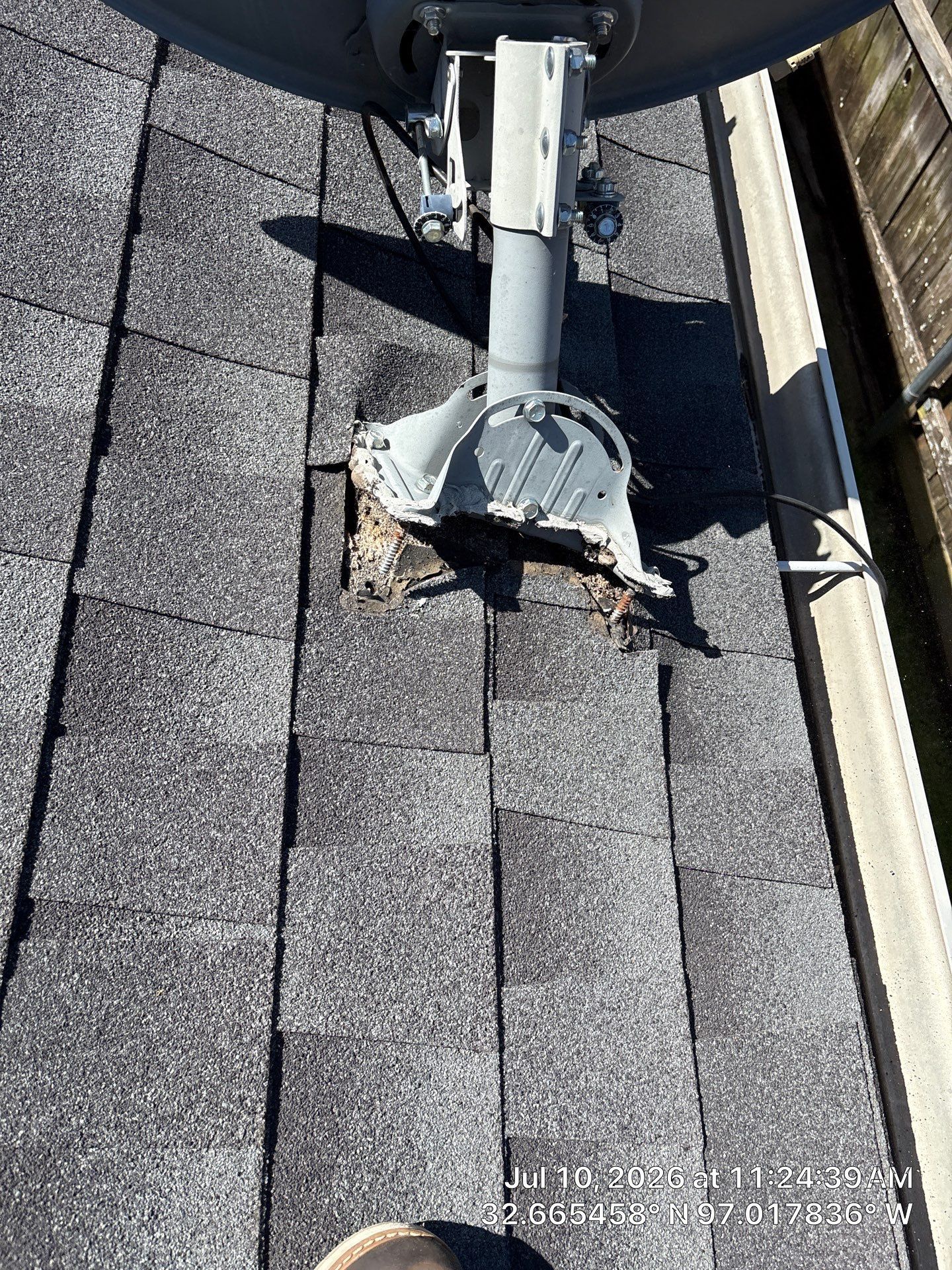 Roof vent pipe with flashing on gray shingles, showing a damaged opening around the base.