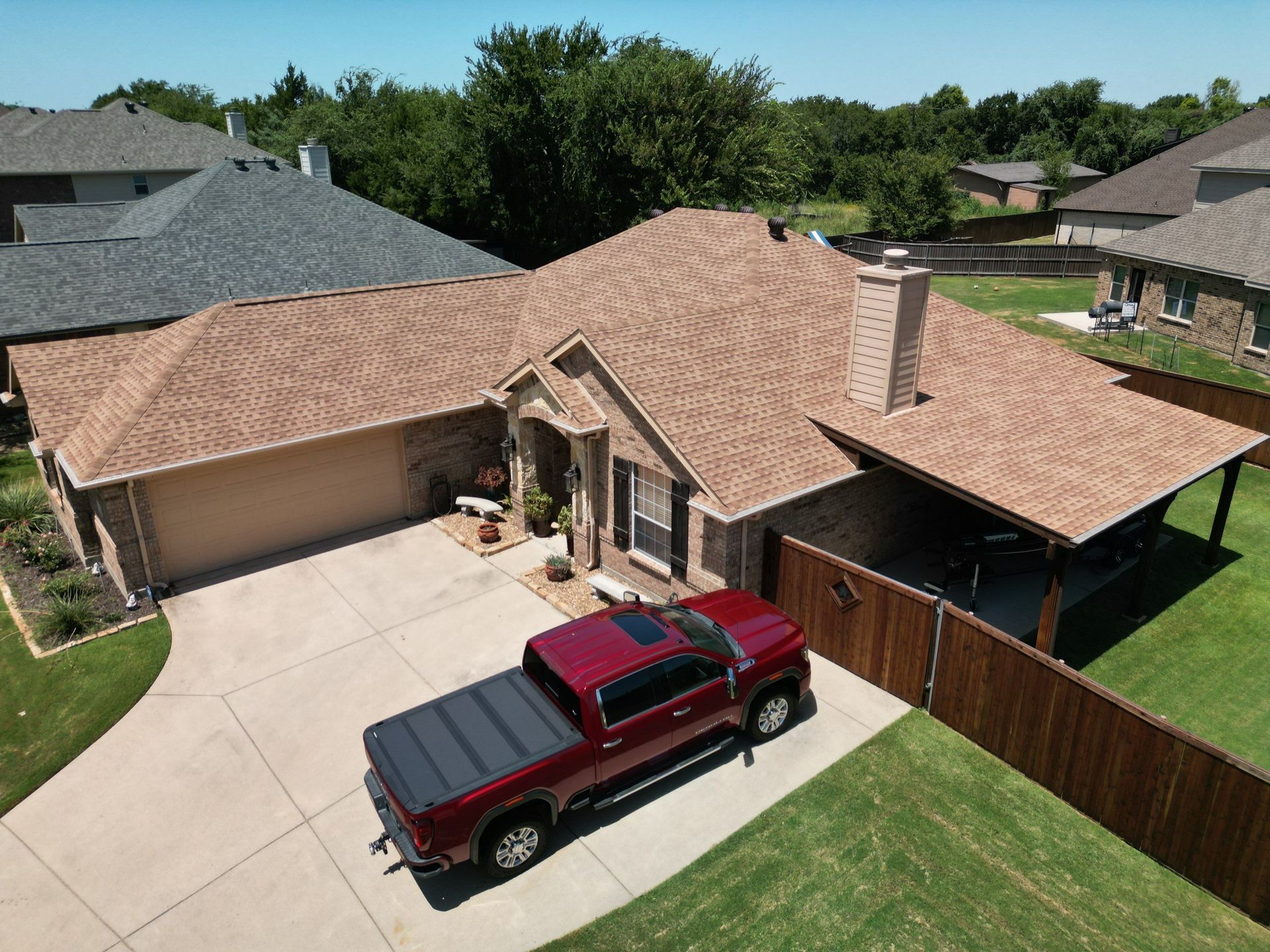 Suburban house with tan roof, driveway, and a red pickup truck parked outside