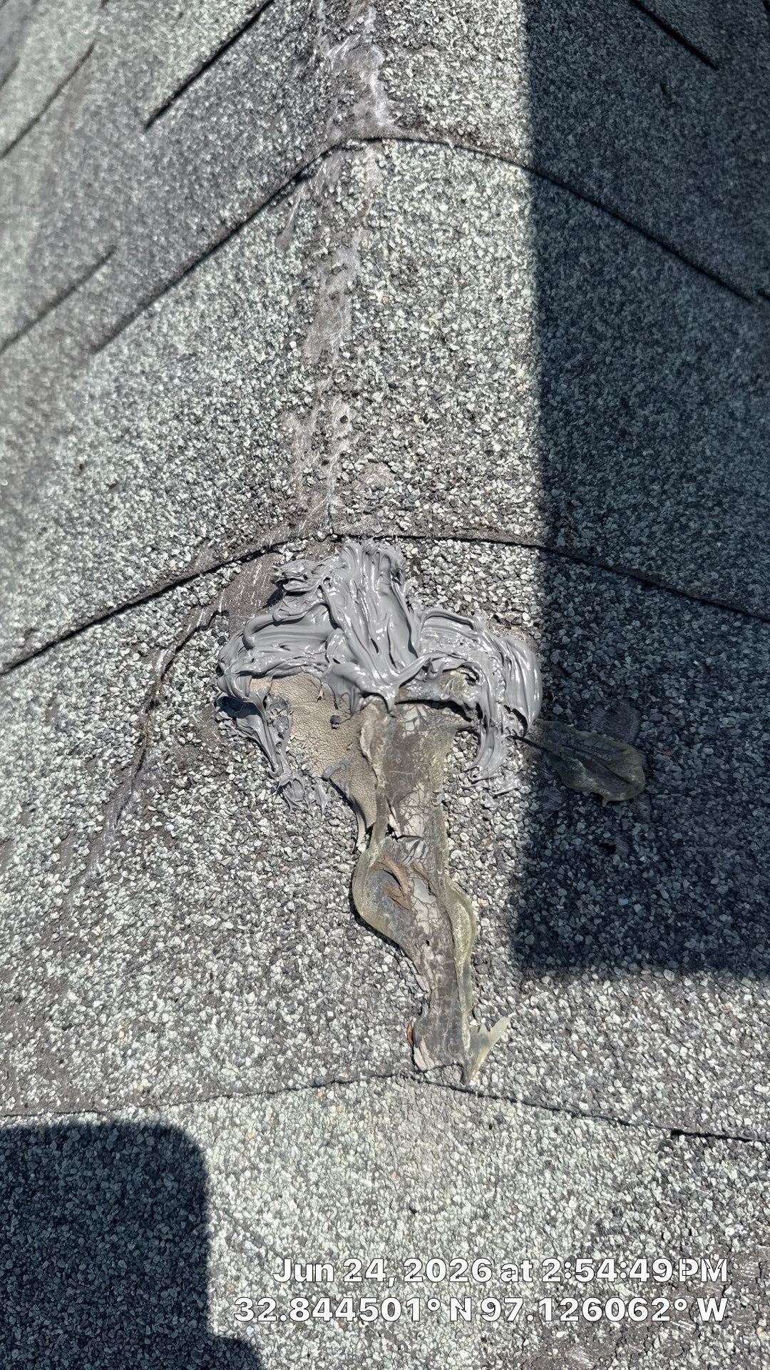 Damaged gray shingle roof with a torn patch near the ridge