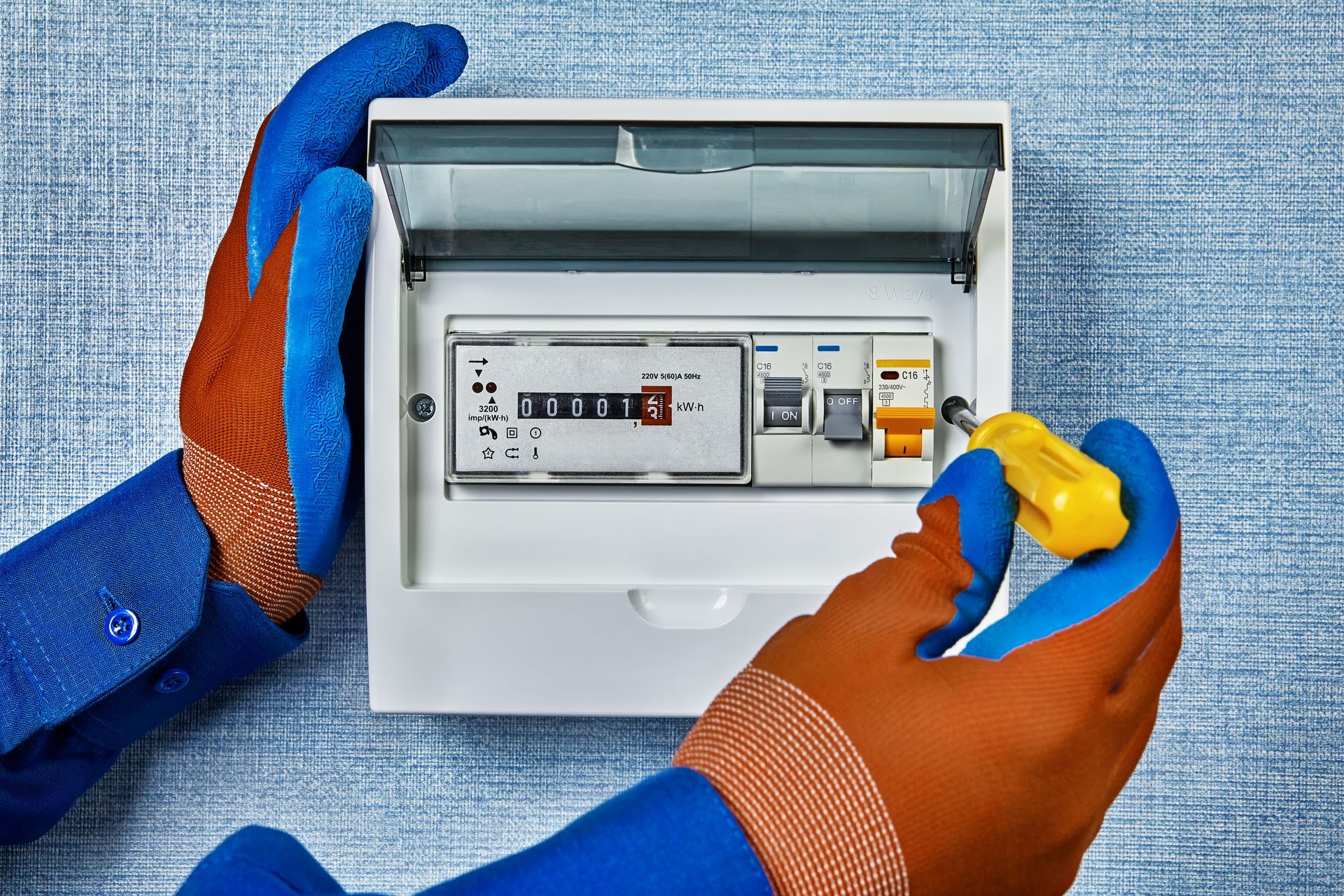 Gloved hands opening an electrical meter box with circuit breakers inside
