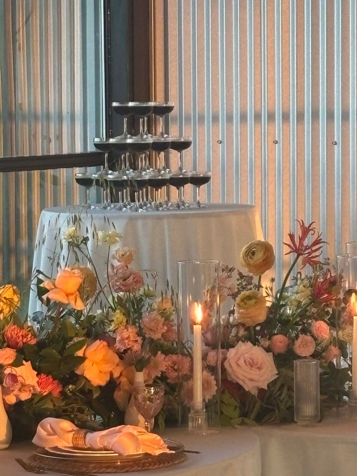 Floral wedding altar with candles, a tiered cake, and pastel flowers on a decorated table